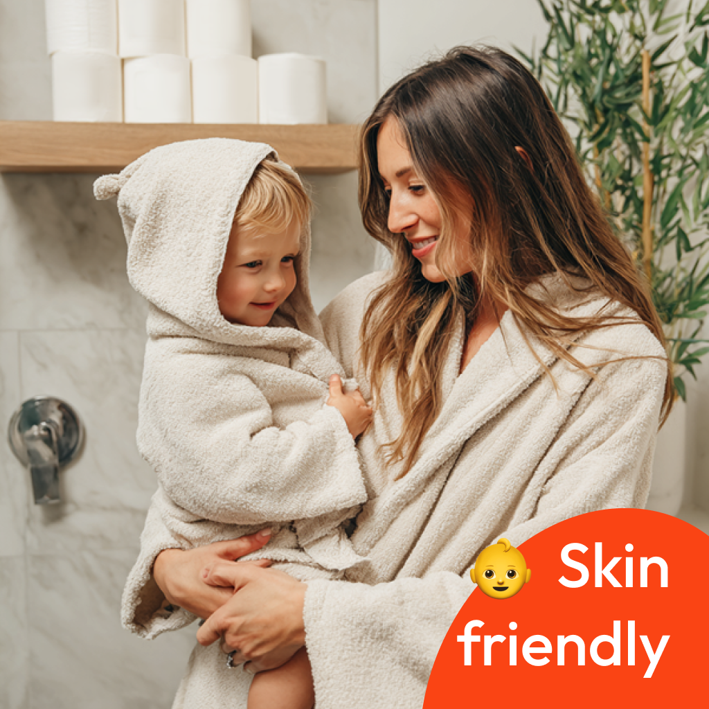 image of mother and baby in a bathroom with rolls of white bamboo toilet paper on a shelf in the background